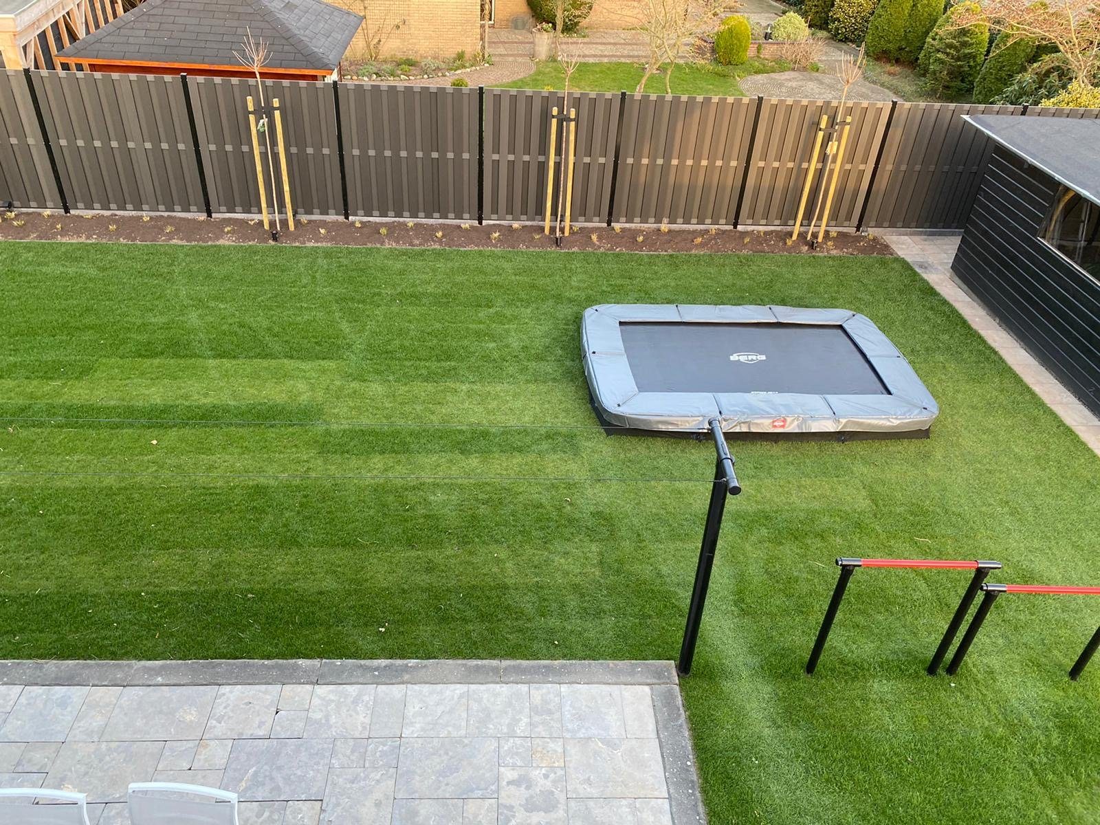 Achtertuin met nieuw gazon, terras en ingebouwde trampoline
